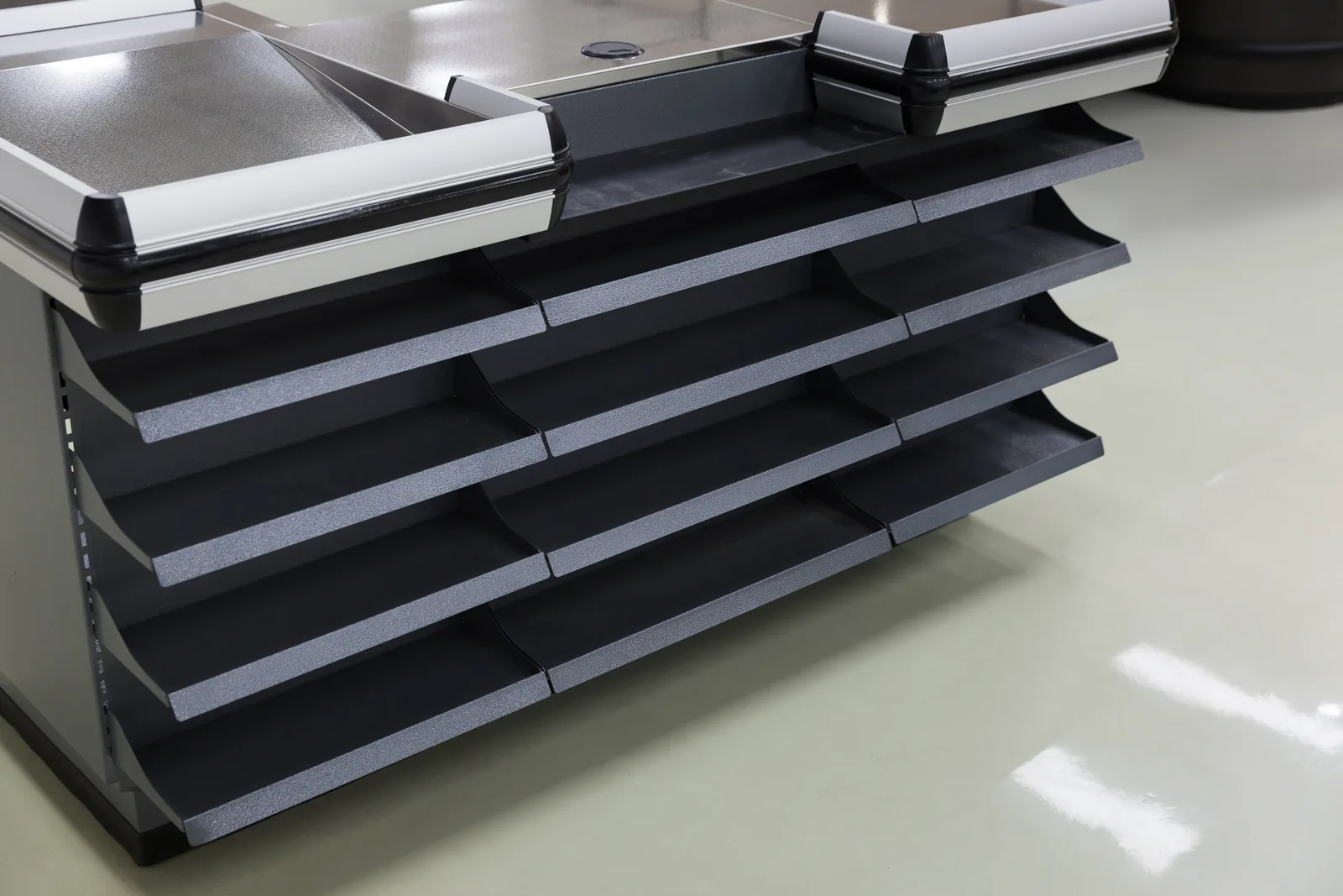 Close view of the impulse shelf tiers and the stainless top edge on a Keshun supermarket checkout counter