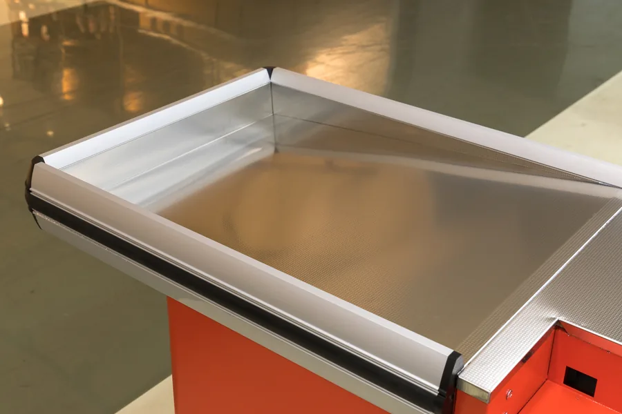 Rolled aluminium alloy border closing the edge of an embossed stainless steel packing tray