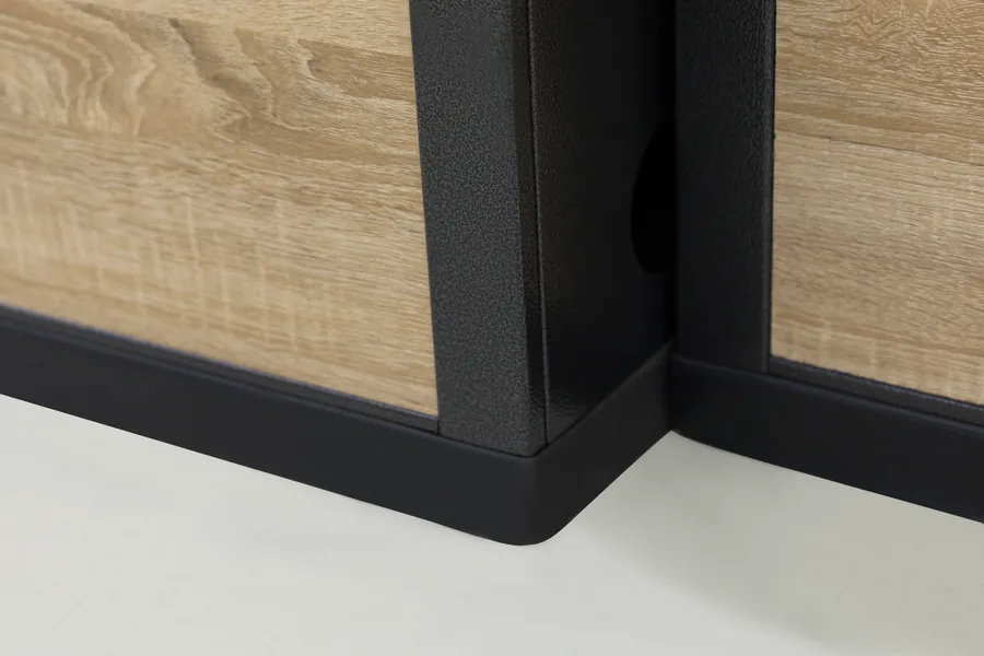 Corner of a wood faced checkout counter carcase meeting the black steel plinth at floor level