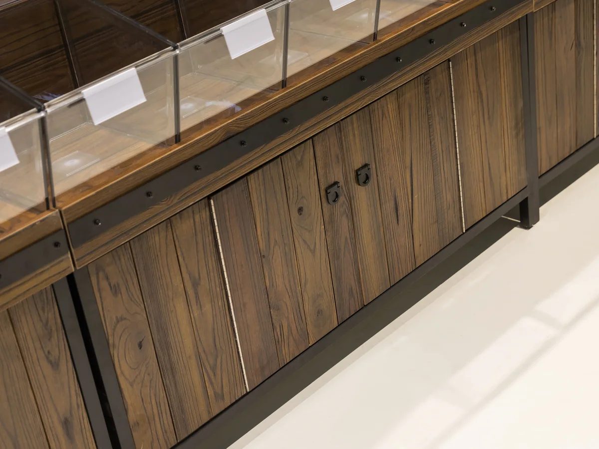 Close-up of the timber cabinet doors with recessed handles below the bin rows