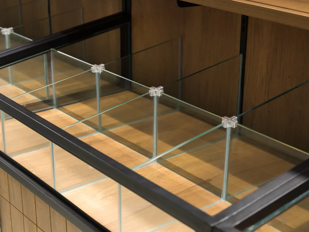 Close-up of the glass panel held in the slim black steel rail dividing the two decks