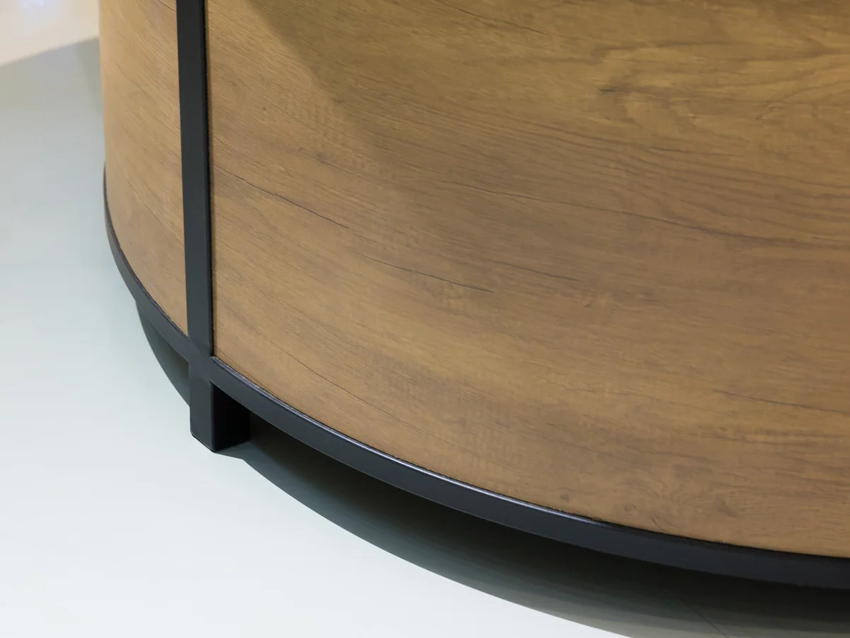 Close-up of the curved timber end panel meeting the black base ring