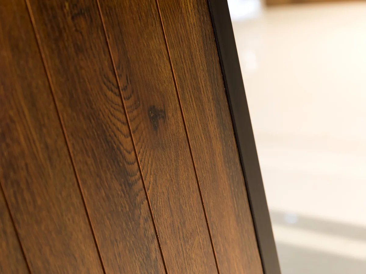Close-up of the dark timber panel showing the vertical grain of the board facing