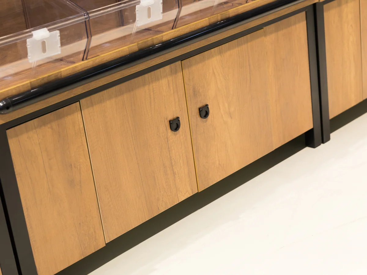 Close-up of the golden timber cabinet doors with recessed handles beneath the bins
