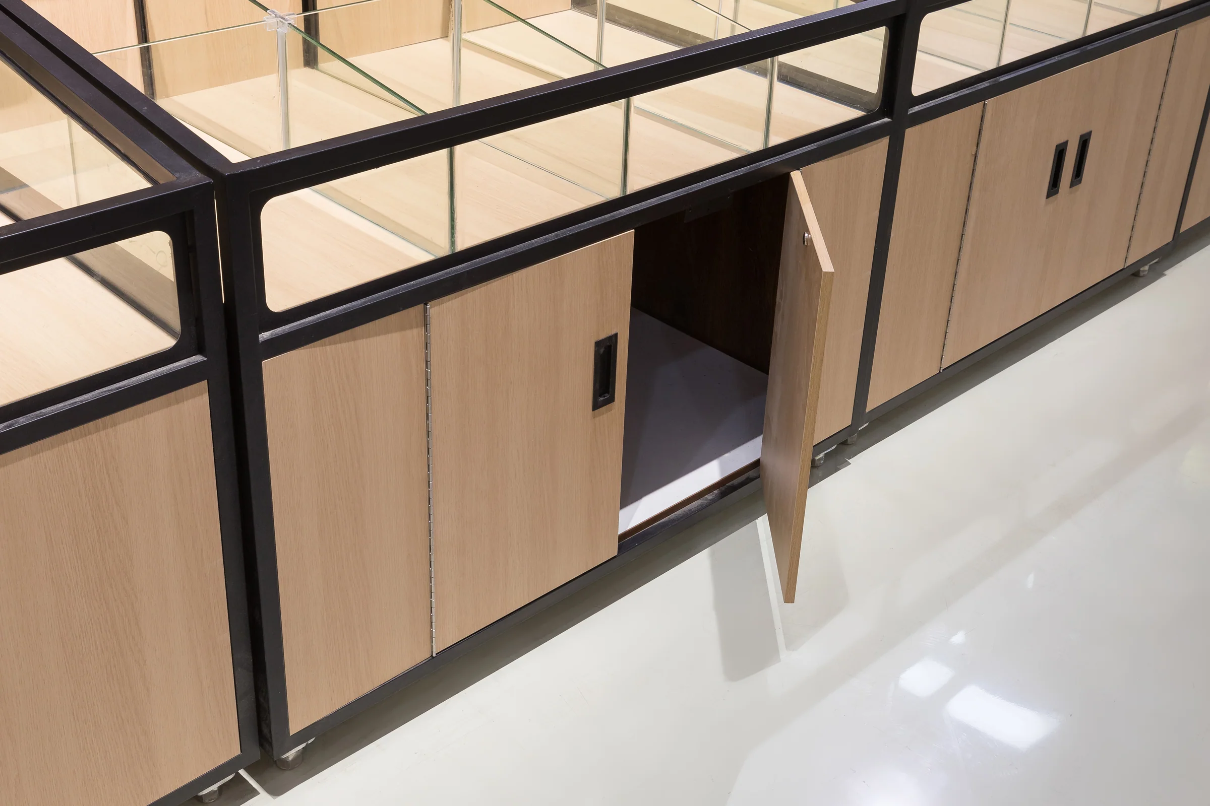Keshun twin bay glazed bulk island with black steel frame, glass panels and a pale worktop
