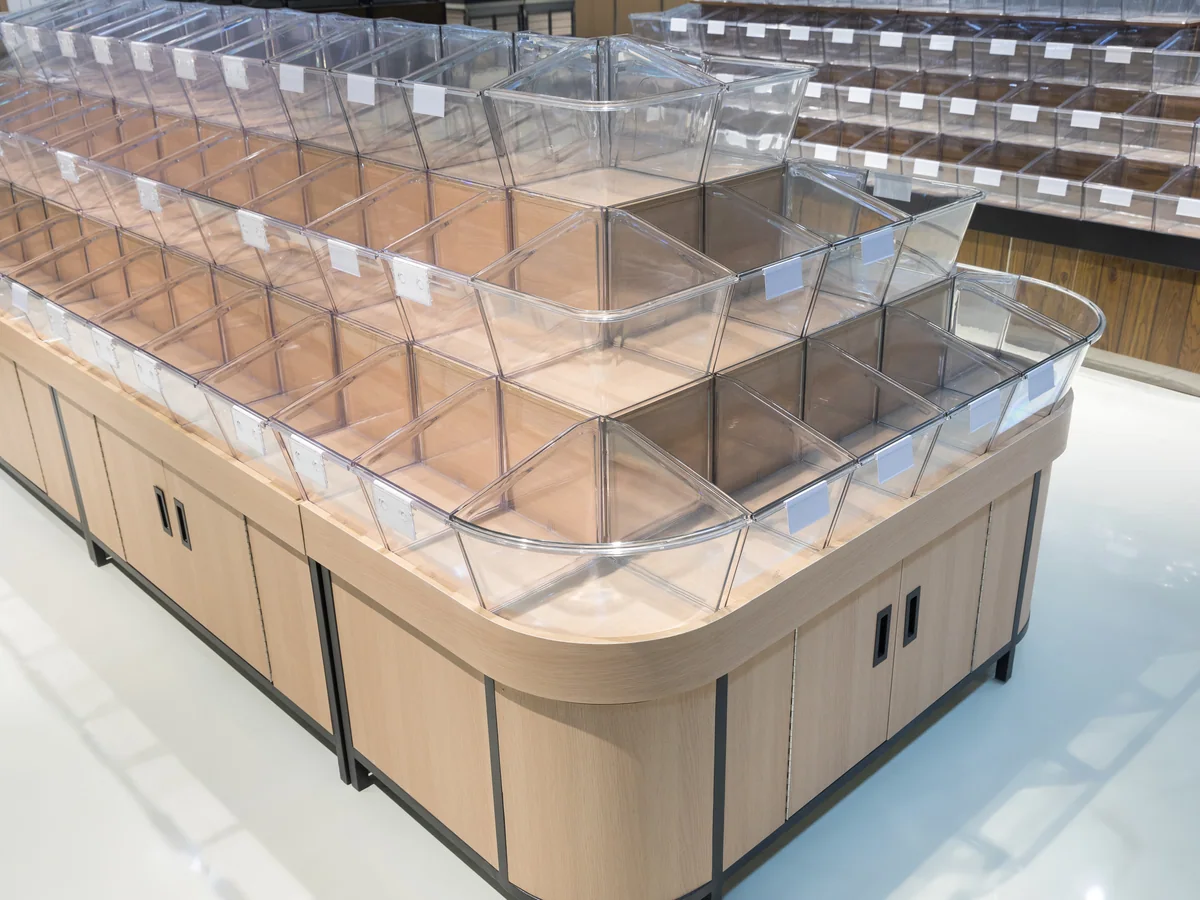 Close-up of the four stepped rows of clear tilt bins on the pale timber island