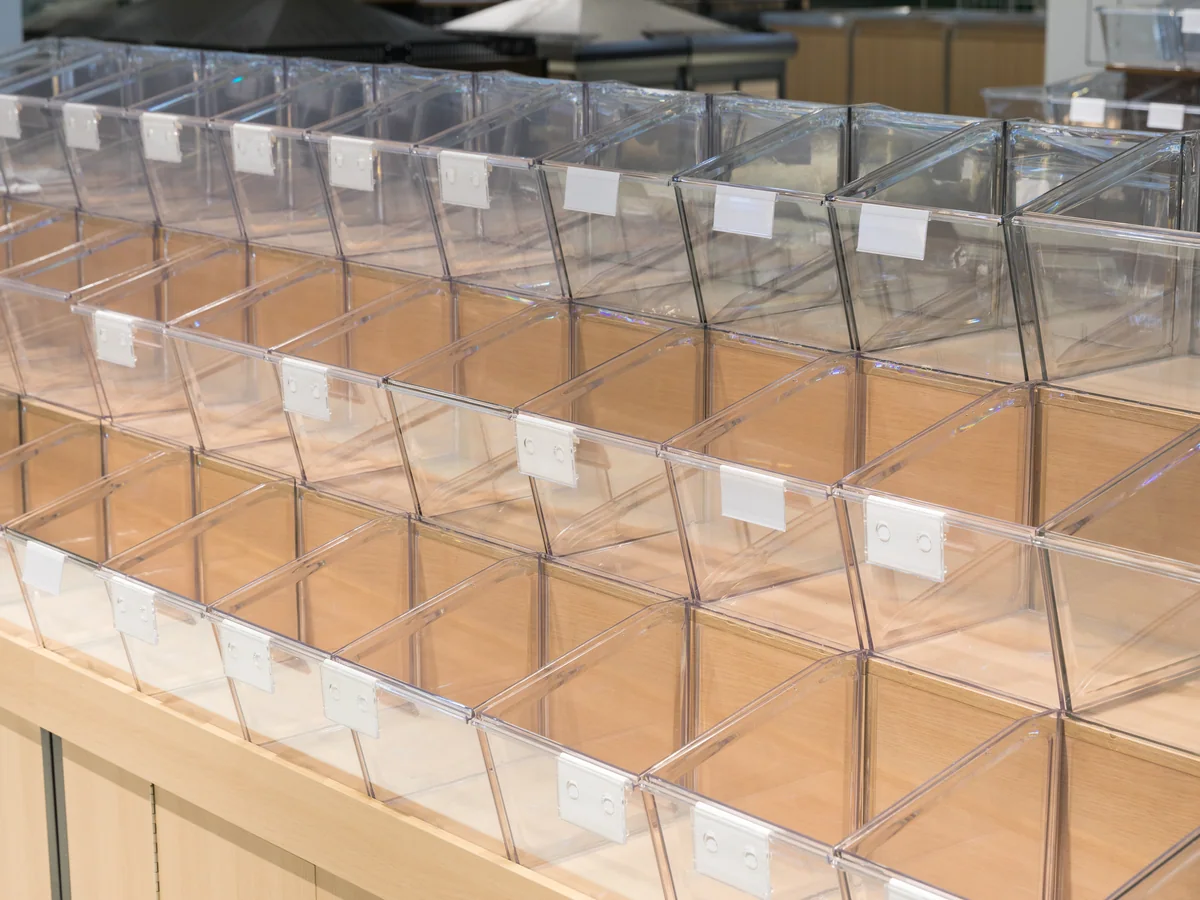 Close-up of a full row of clear tilt bins with ticket holders along the front lip