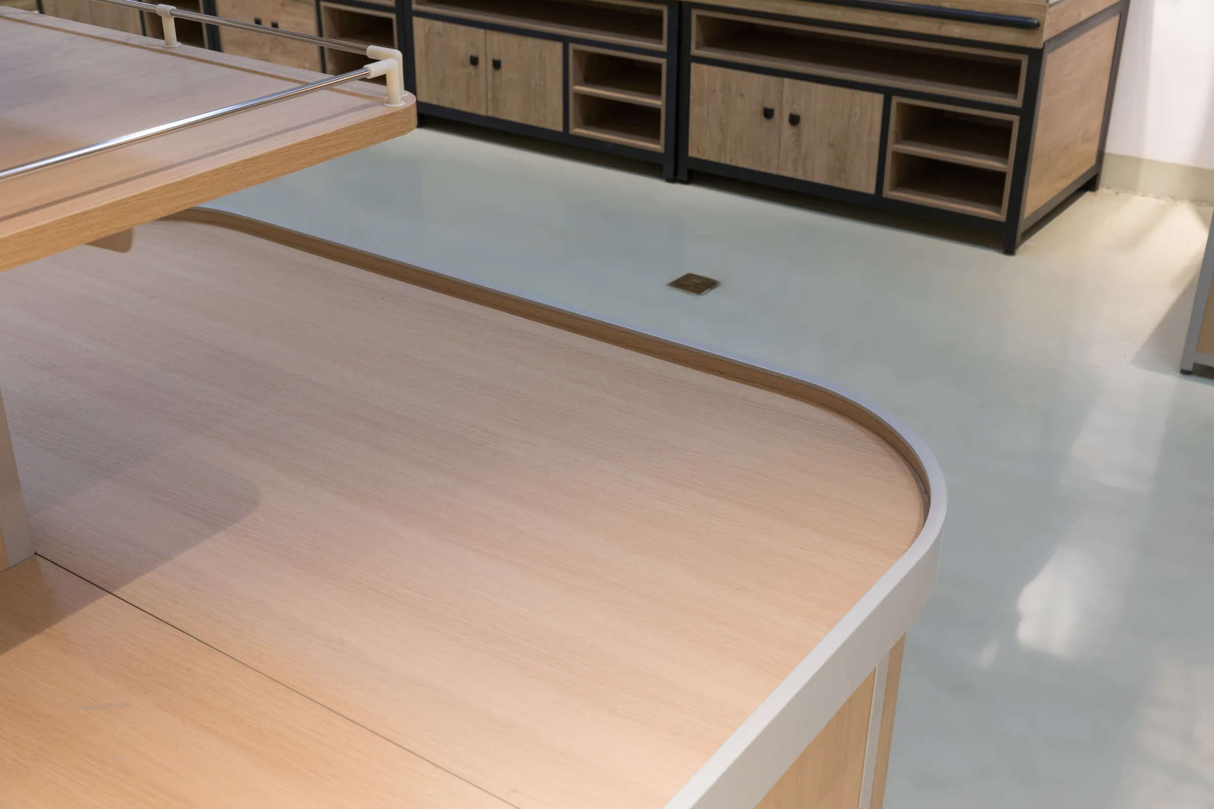 Keshun pale top bulk island with an open worktop deck, light timber cabinets and a raised upper shelf