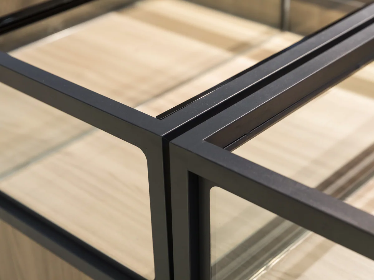 Close-up of the black steel frame corner where the glass panels meet