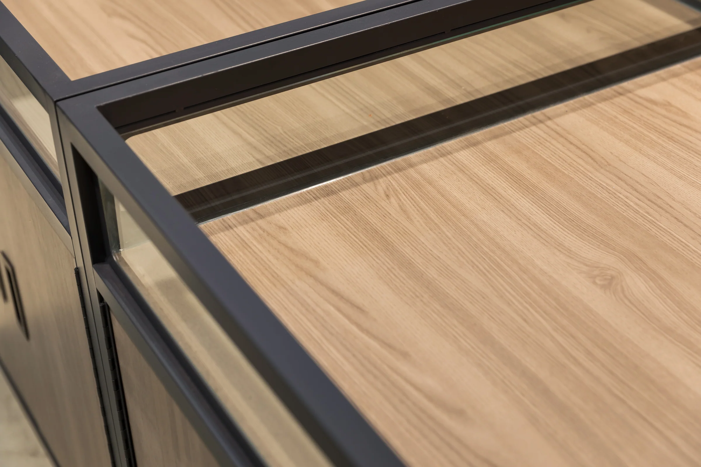 Keshun four sided glazed island cabinet with tall glass panels and a light timber base