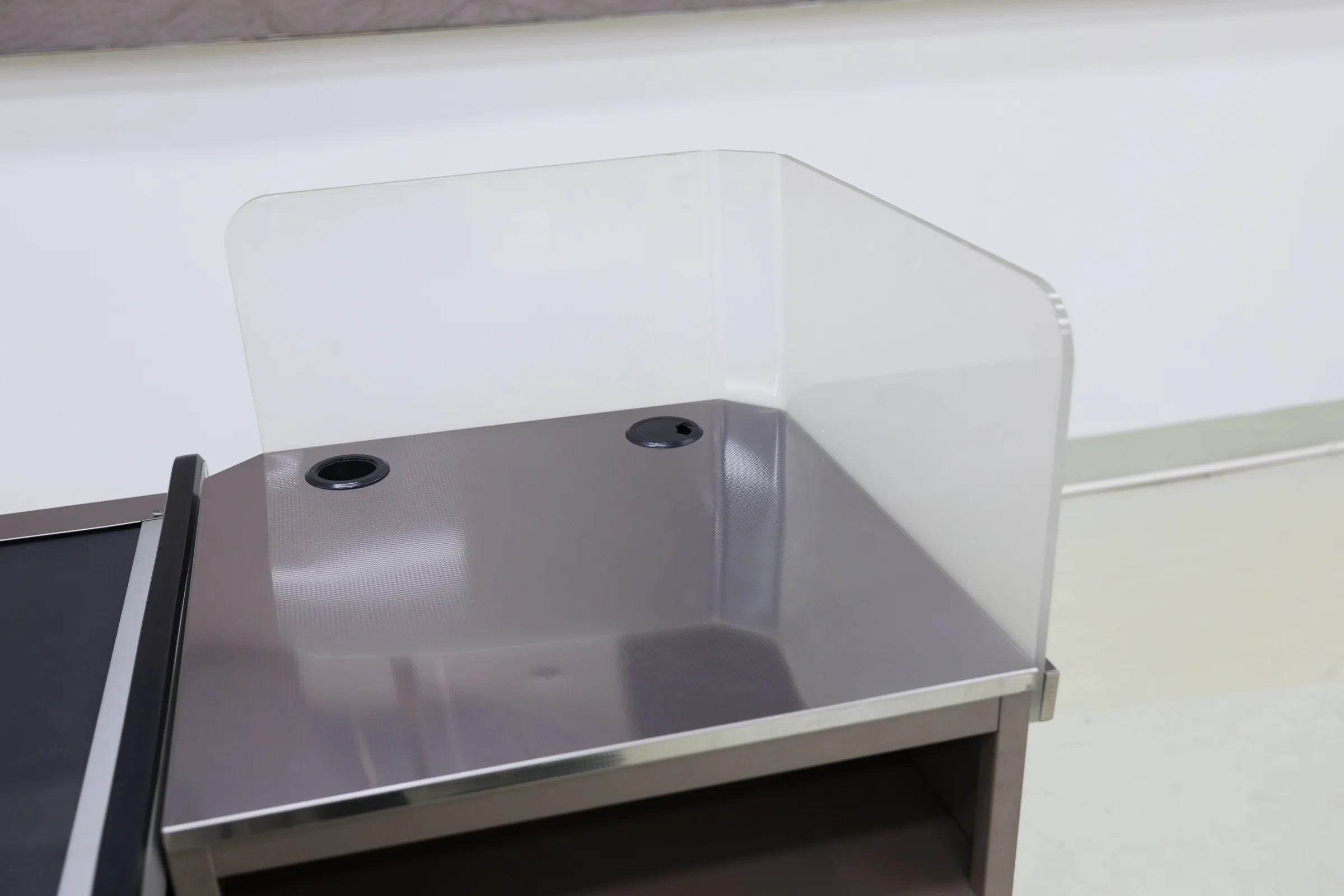 Cream and stainless Keshun cashier counter with a drawer bank and a raised end screen in the showroom