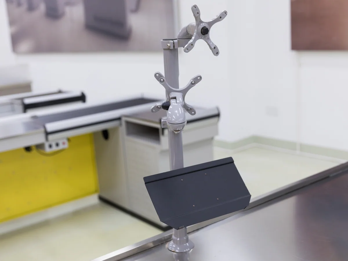Column arm carrying the monitor and scanner above the deck of a Keshun cashier counter