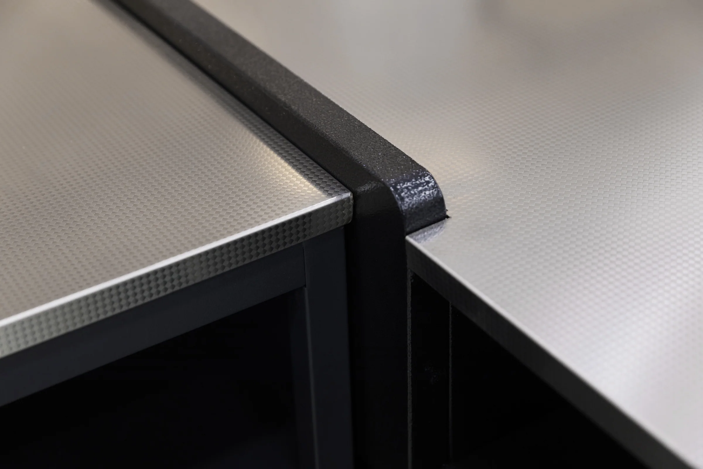 Keshun charcoal checkout counter with a single bright horizontal accent band across the front panel
