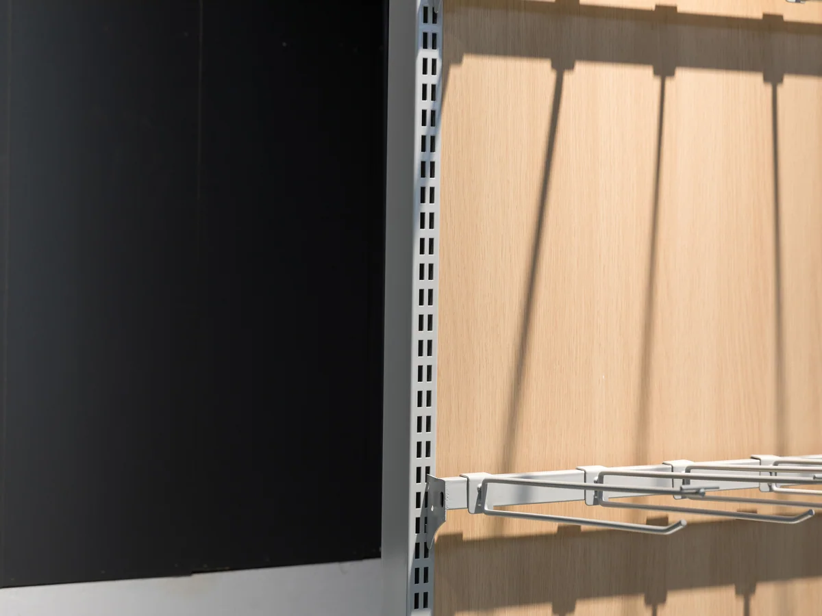 Close-up of the pale timber back panel behind the shelf arms