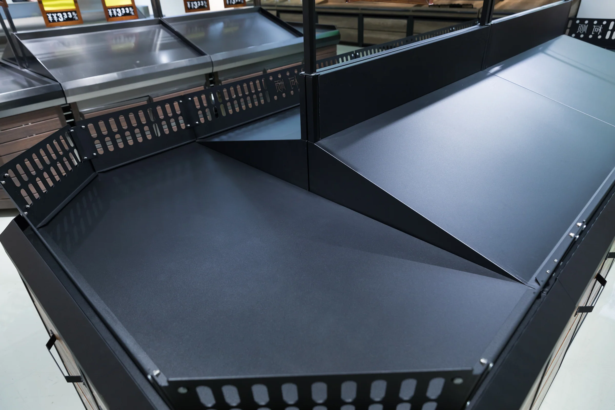 Keshun dark timber produce island edged with black plastic crates and a sign rig above