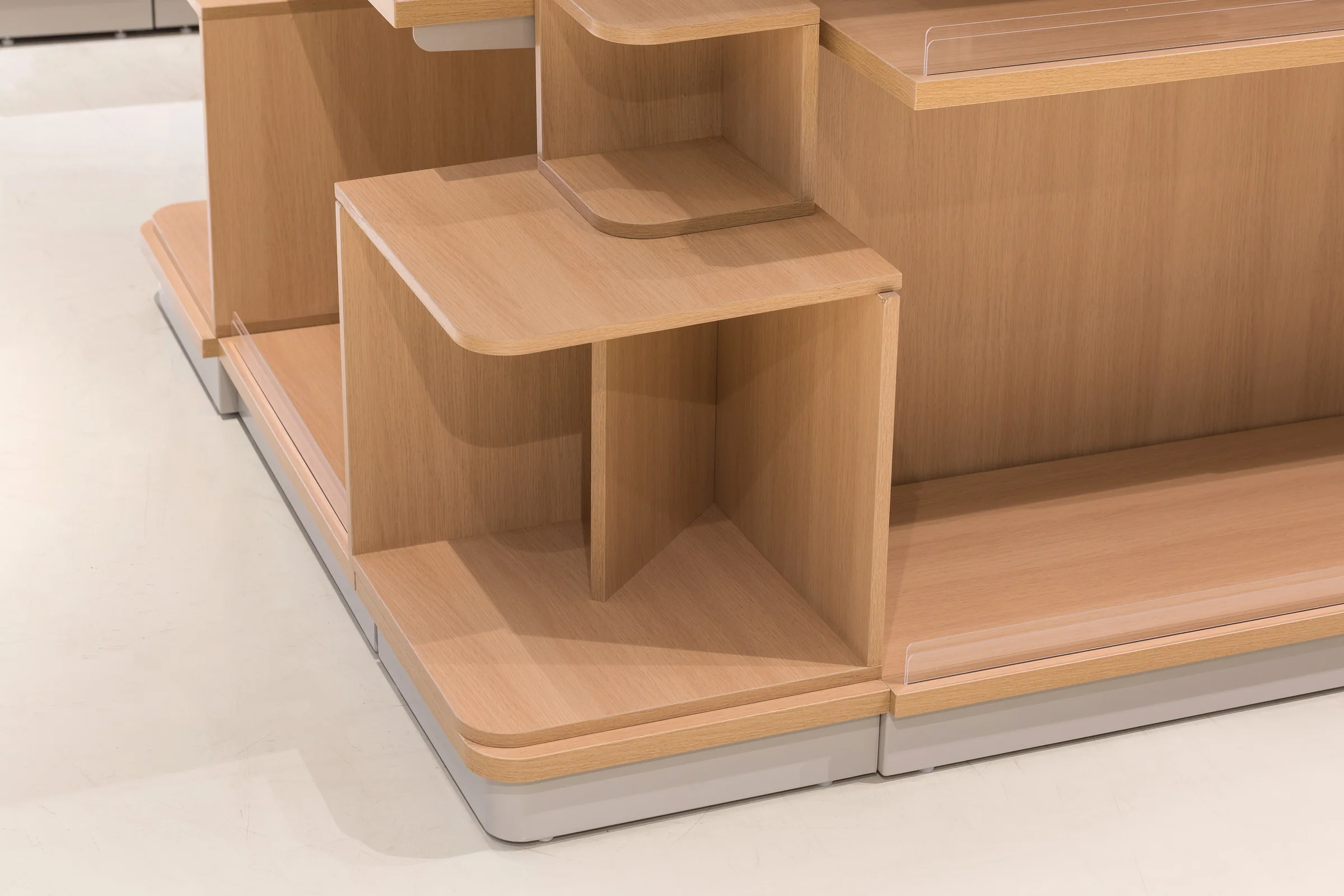 Keshun multi-tier pale timber promotional display with angled shelves presenting facings forward