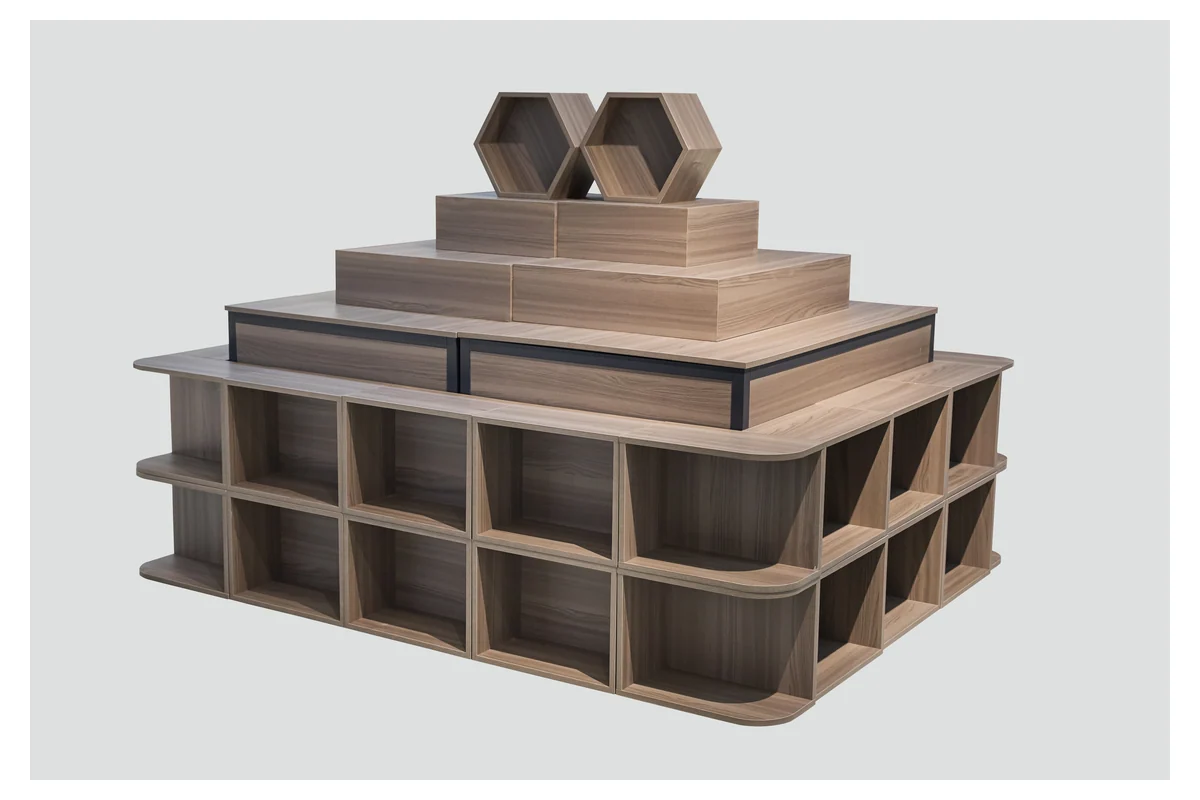 Light timber stepped supermarket promotion table with a closed base and tiered top