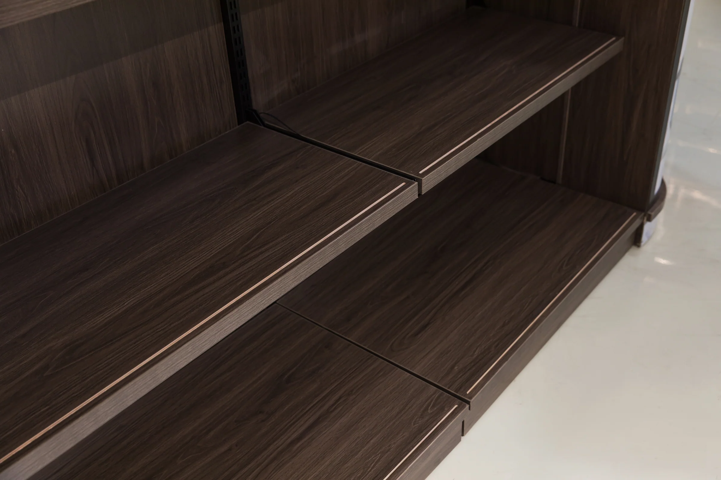 Keshun low double sided island gondola in dark timber with a curved end and poster panel