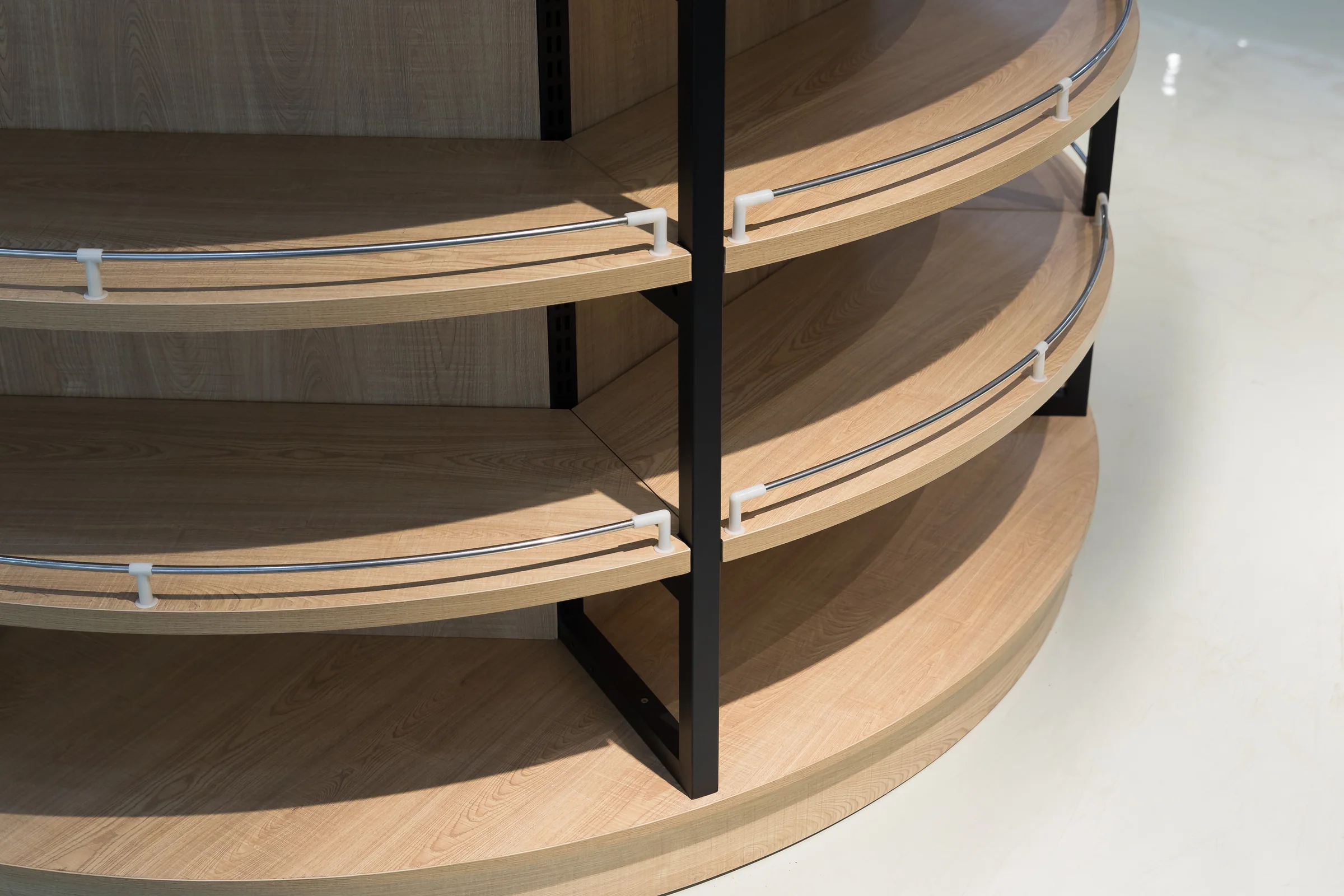 Keshun full height circular shelving column with pale timber shelf rings in a black steel frame