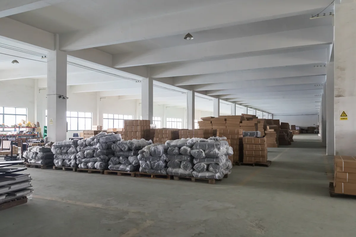 Palletised and stretch-wrapped supermarket equipment stacked in the Keshun workshop bay at Changshu before loading